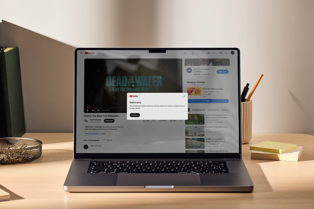 A laptop displays a watch time reminder pop-up over a YouTube video.